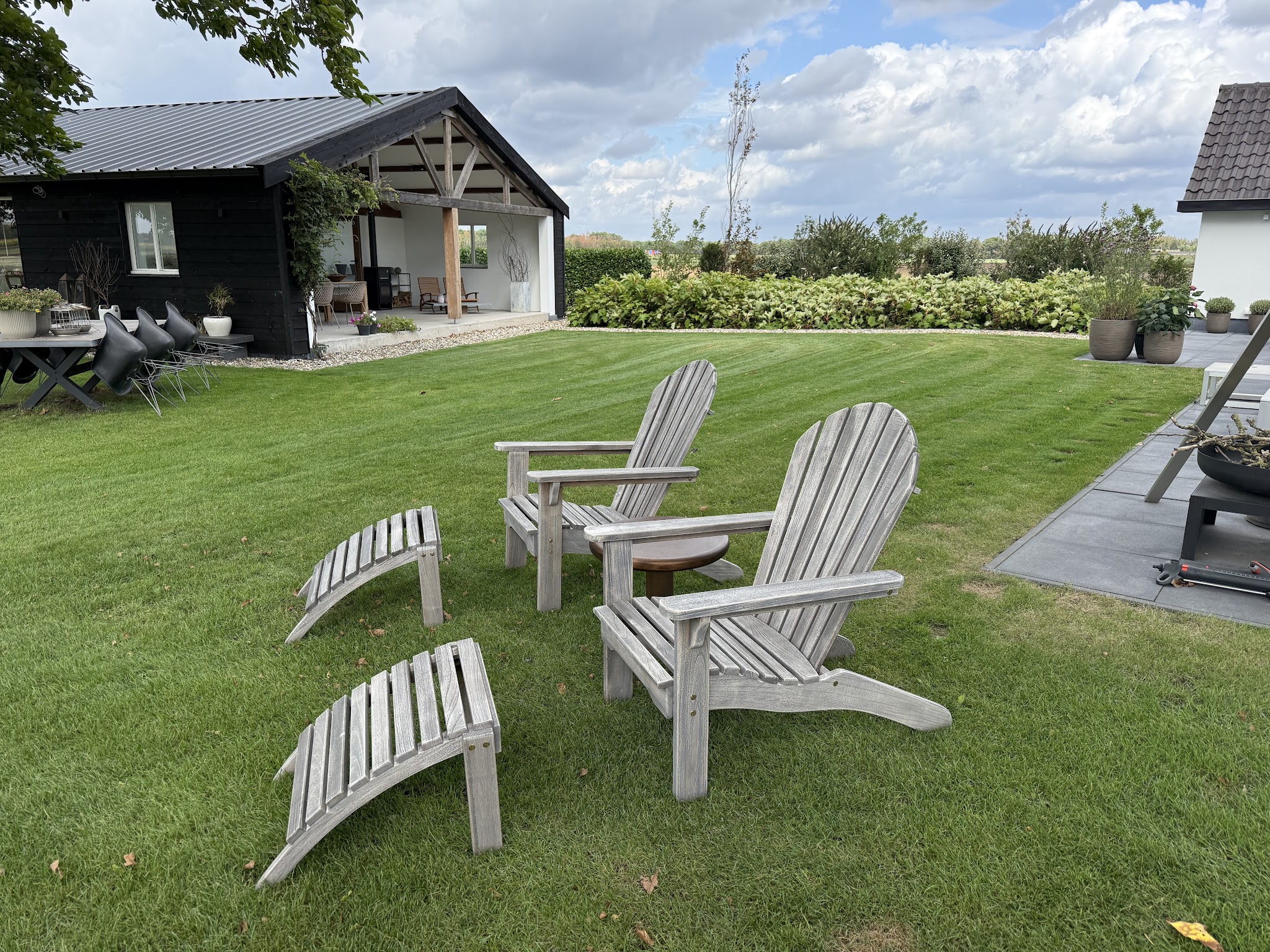 Gestreept gazon met houten tuinstoelen voor een zwarte veranda