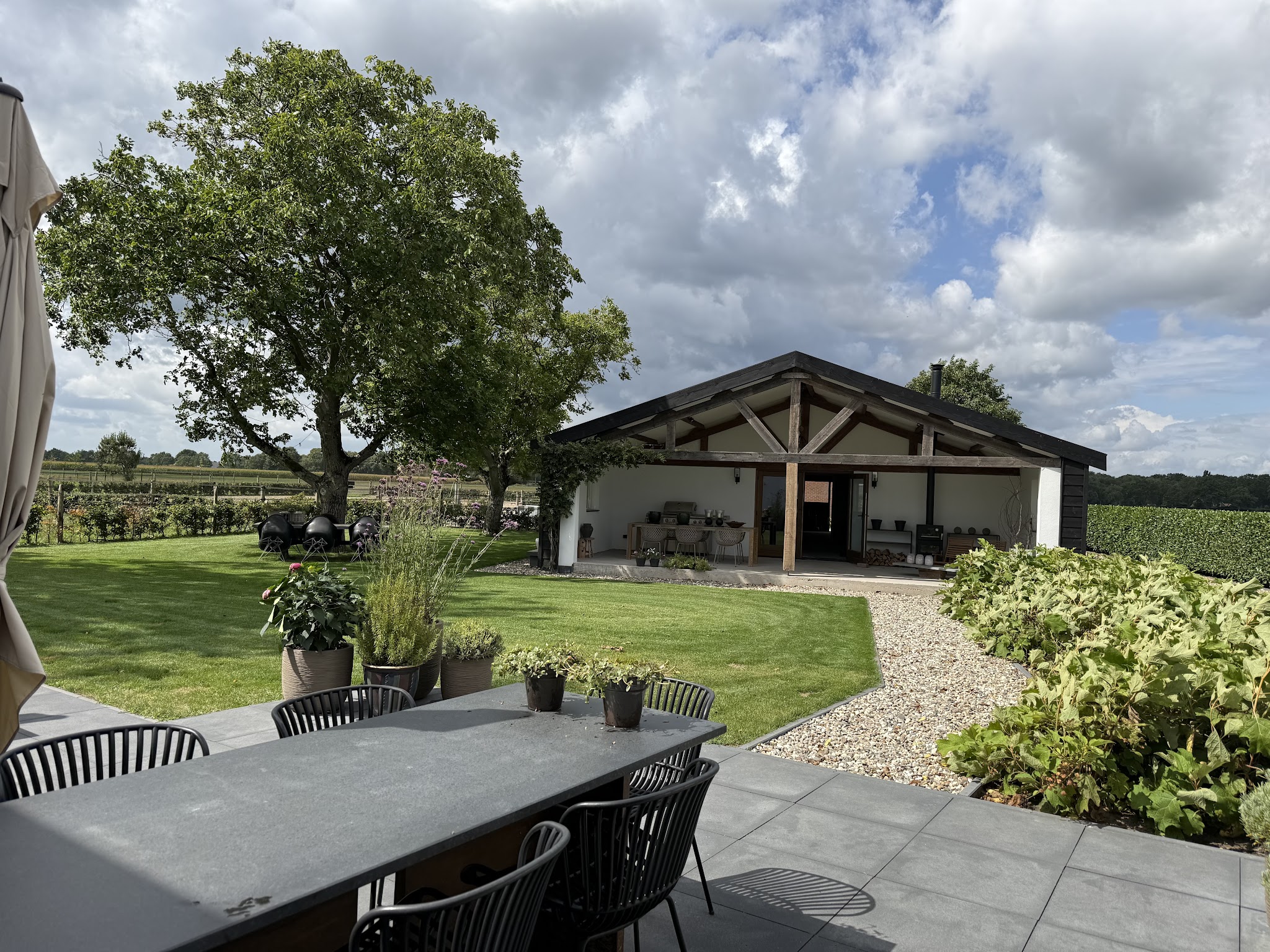 Eettafel op het terras met zicht op het gazon, de eik en de veranda